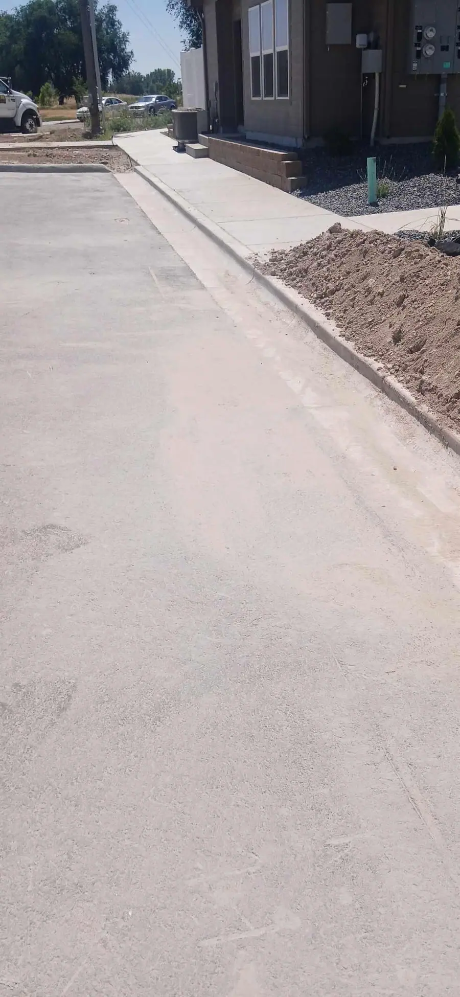A swept concrete drive and new curb beside a newly built building