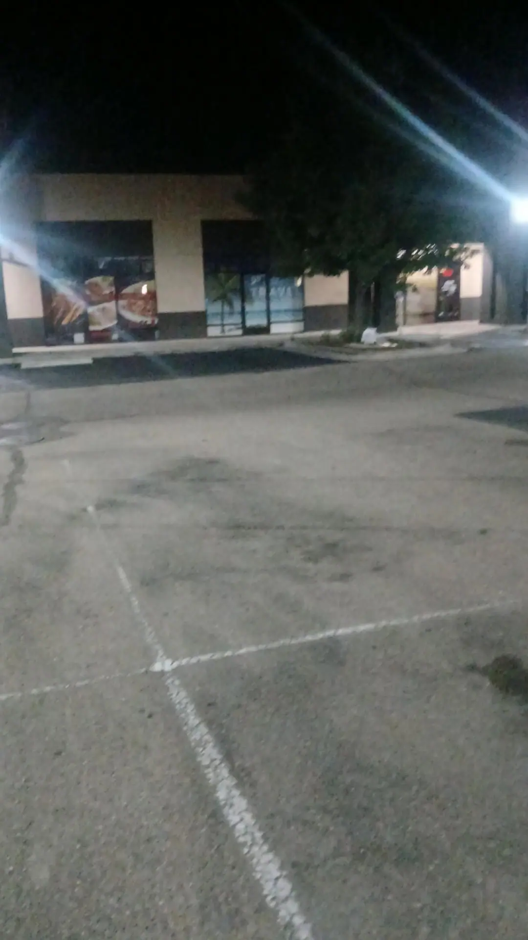 A strip center parking lot with white stall lines at night